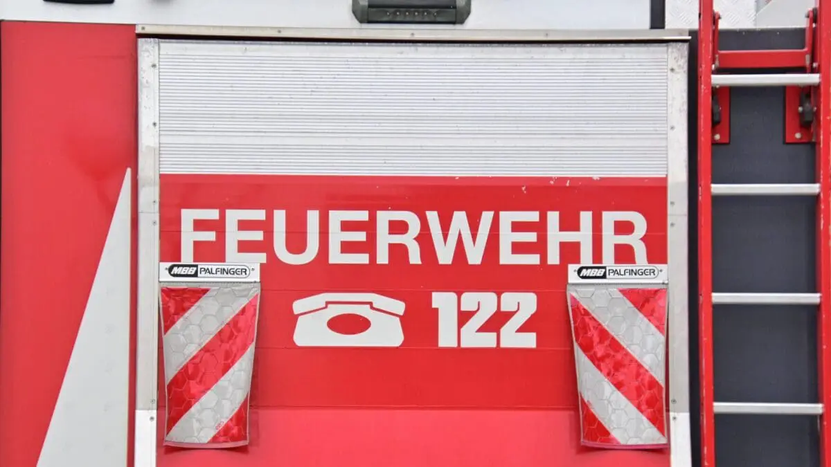Rote Rückseite eines Feuerwehrfahrzeugs mit Aufschrift Feuerwehr und Notrufnummer 122