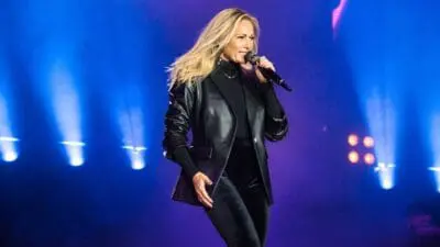 Helene Fischer singt auf der Bühne mit einem Mikrofon in der Hand unter blauen Scheinwerfern