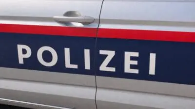 Nahaufnahme der Tür eines silbernen Polizeiautos mit der Aufschrift POLIZEI auf blauem Grund.