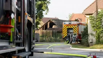 Feuerwehrfahrzeuge und ausgerollte Schläuche vor einer beschädigten Scheune in Zellerndorf