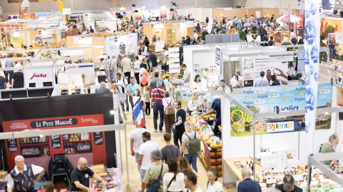 Blick in eine belebte Messehalle mit zahlreichen Ausstellungsständen und Besuchern auf der Klagenfurter Herbstmesse