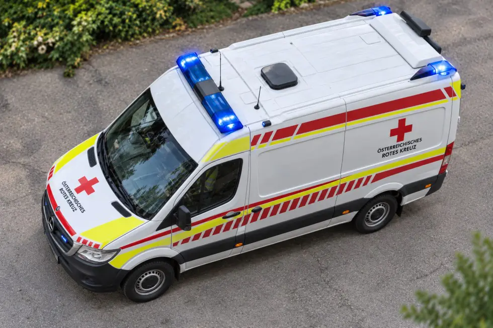 Ein Rettungswagen des Österreichischen Roten Kreuzes mit eingeschaltetem Blaulicht auf einer Straße
