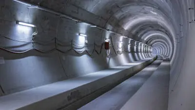 Beleuchteter Betonbahntunnel mit Kabeln und seitlichen Wartungswegen