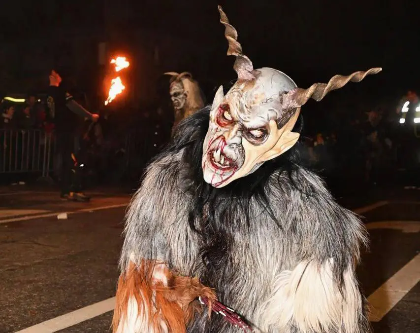 Eine gehörnte Perchtenfigur im zotteligen Fellkostüm bei einem nächtlichen Lauf.
