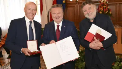 Bürgermeister Michael Ludwig steht mit Lukas und Peter Resetarits und den Ehrenzeichen im Wiener Rathaus.