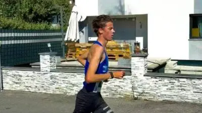 Läufer in blauem Trikot und schwarzen Shorts auf einer Straße