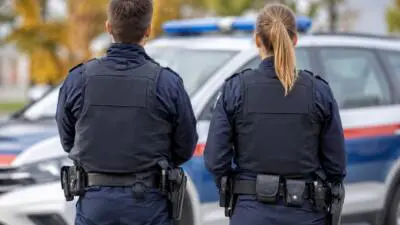 KI-Symbolbild: Zwei uniformierte Personen stehen vor einem Einsatzfahrzeug.