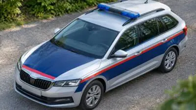 KI-Symbolbild: Ein silberner Kombi mit blau-roten Streifen und Blaulichtbalken.