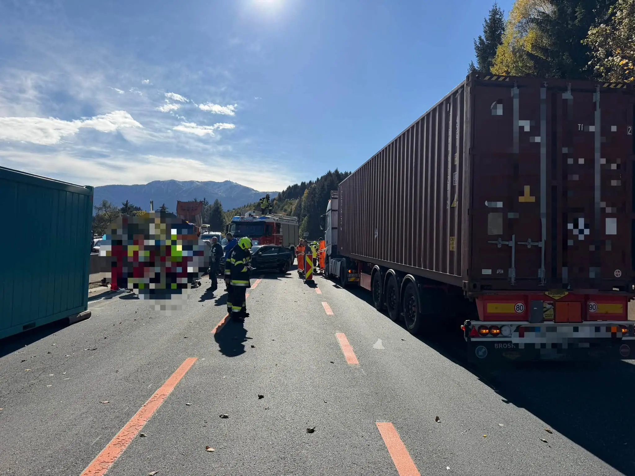 Einsatzkräfte stehen zwischen einem Lastwagen, einem Feuerwehrfahrzeug und weiteren Fahrzeugen auf der Straße.