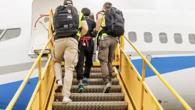Eine Person steigt begleitet über eine mobile Treppe in ein Flugzeug.