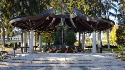Gedenkstätte mit Kränzen unter einem überdachten Pavillon auf einem Friedhof
