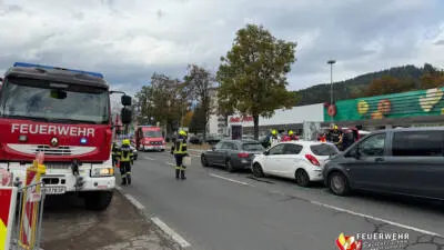 Feuerwehrkräfte stehen neben Einsatzfahrzeugen und Autos auf der Villacher Straße in Spittal.