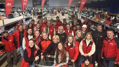 Ein Team steht zwischen Wintersportartikeln und AK-Kärnten-Fahnen in einer Verkaufshalle.