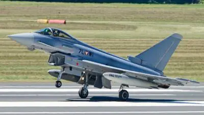 Ein grauer Kampfjet rollt über die Start- und Landebahn eines Flugplatzes.