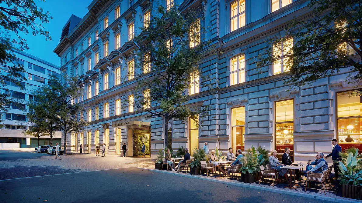 Historische Fassade des Schillerhofs mit beleuchteten Fenstern, Eingang und Gastgarten in Wien