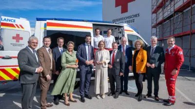 Vertreter der Landesregierung und des Roten Kreuzes vor einem Rettungswagen