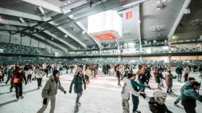 Menschen drehen auf einer überdachten Eisfläche ihre Runden.