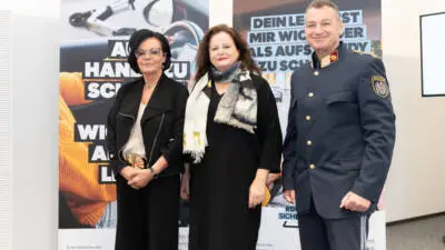 Personen stehen vor Plakaten zur steirischen Verkehrssicherheitskampagne für mehr Rücksicht im Straßenverkehr.