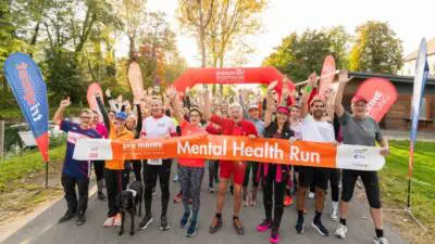 Läuferinnen und Läufer halten beim Mental Health Run ein Banner in die Kamera.