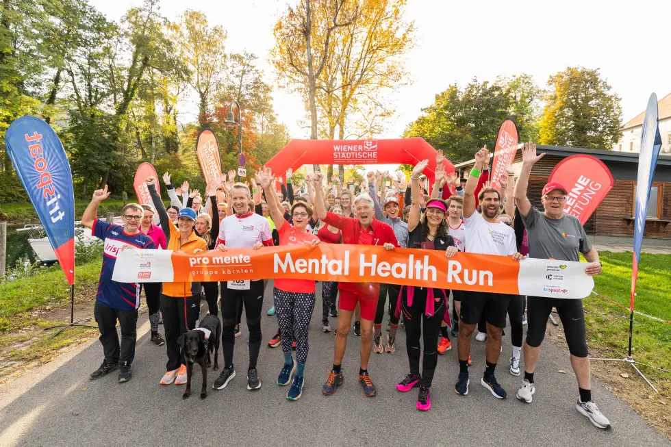 Läuferinnen und Läufer halten beim Mental Health Run ein Banner in die Kamera.