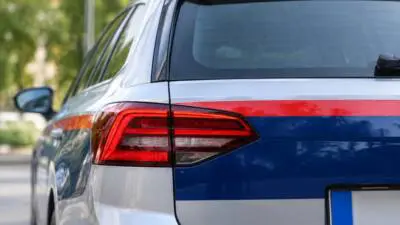 Nahaufnahme des Hecks eines weiß-blau-roten Polizeikombis mit Rückleuchten und Blaulichtaufsatz