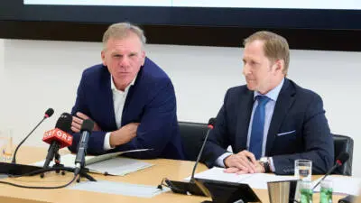 Zwei Männer sitzen mit Mikrofonen an einem Tisch