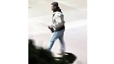 Unscharfe Aufnahme eines Mannes in heller Jacke und Jeans beim Gehen.