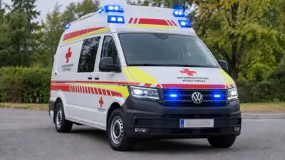Einsatzfahrzeug des Österreichischen Roten Kreuzes mit eingeschaltetem Blaulicht auf einer Straße
