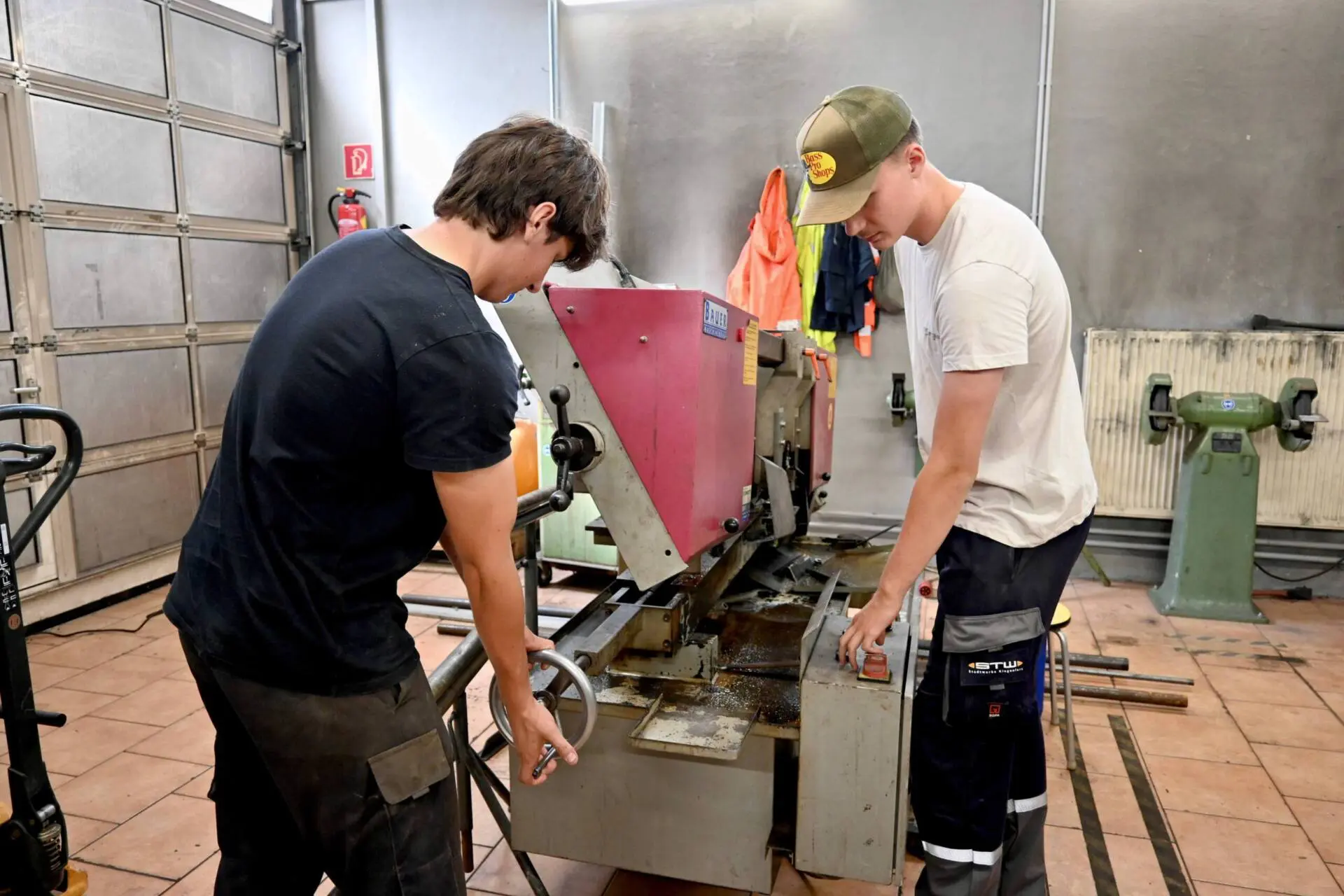 Zwei Männer arbeiten an einer Metallbearbeitungsmaschine in einer Werkstatt.