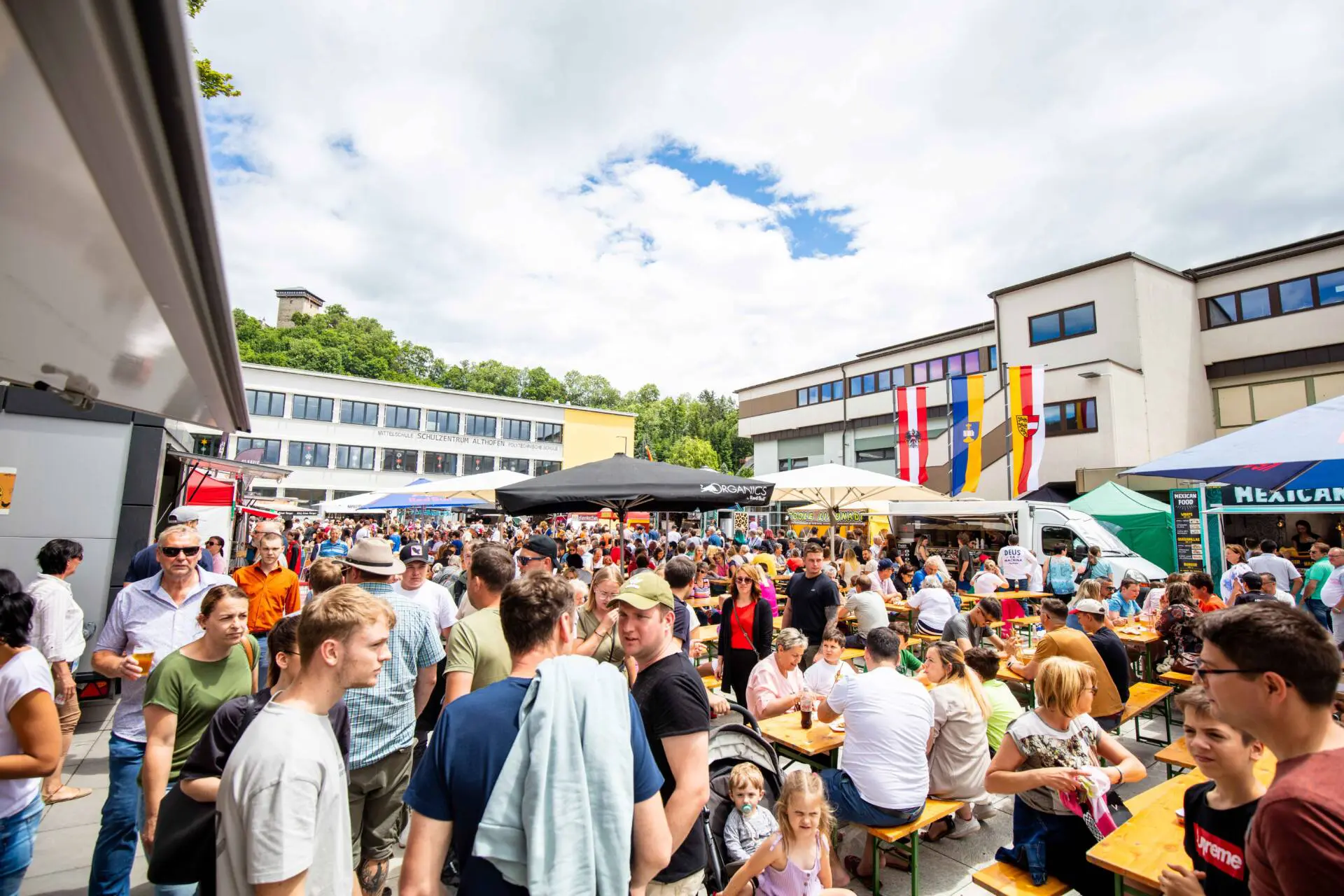 Besucherinnen und Besucher stehen zwischen Street-Food-Ständen und Sitzplätzen im Freien.