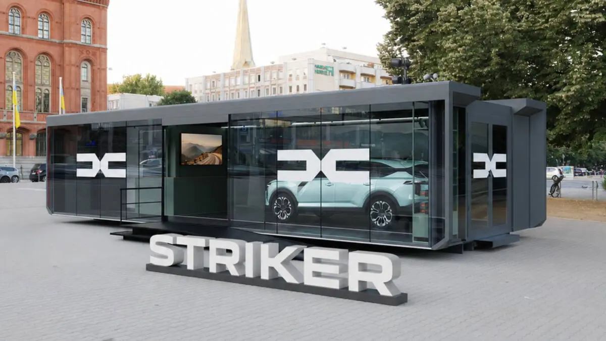 Verglaster STRIKER-Ausstellungsraum mit einem hellen Auto und großen Schriftzügen davor