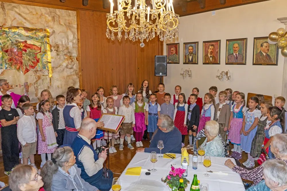 Kinderchor singt vor älteren Gästen in einem festlich geschmückten Saal