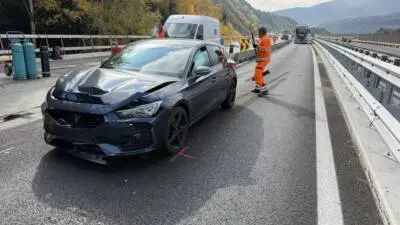 Dunkelgrauer Pkw mit beschädigter Front auf einer Baustellenfahrbahn