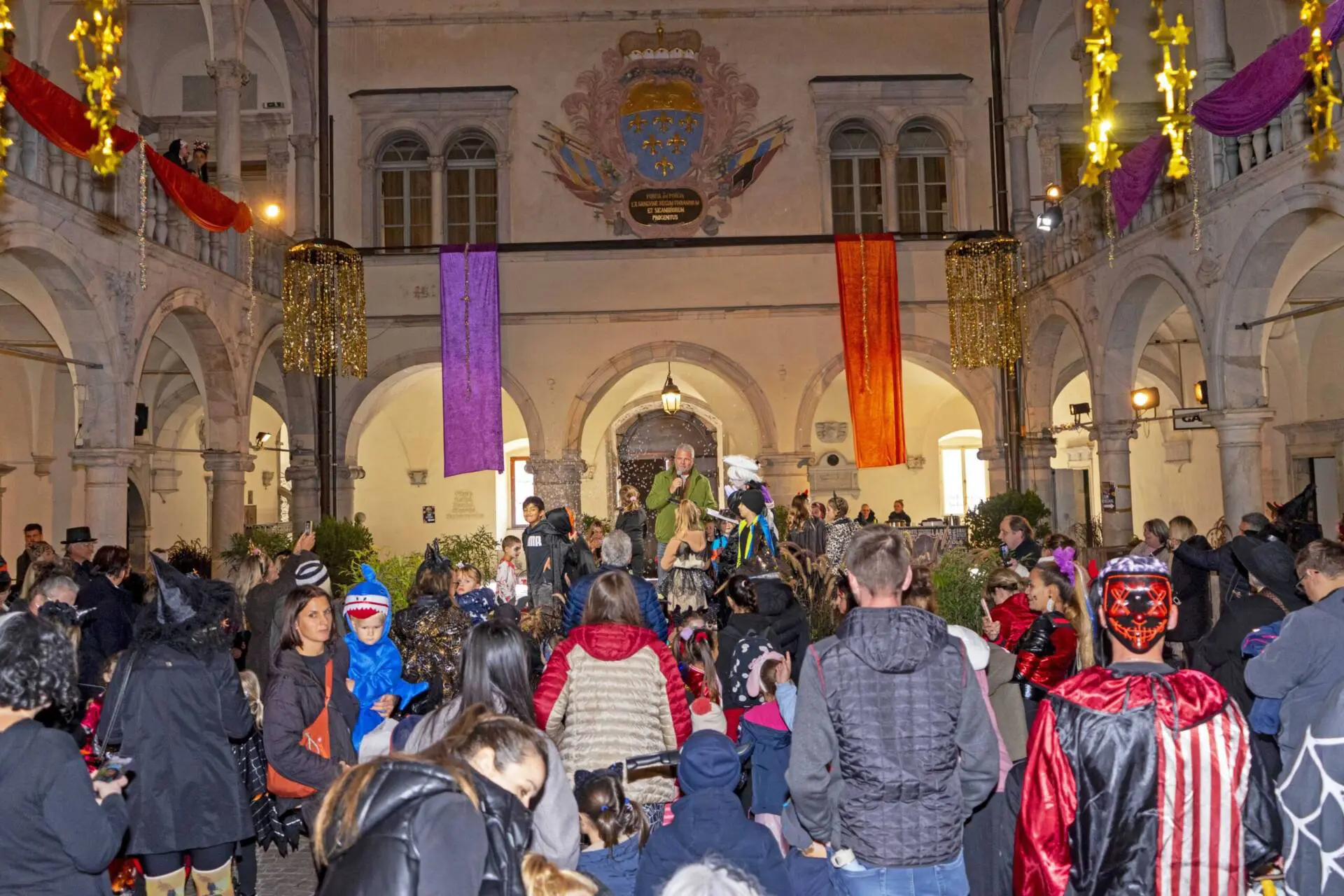 Kostümierte Menschen versammeln sich in einem festlich geschmückten Innenhof.