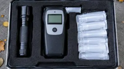 KI-generiertes Bild: Ein Atemalkoholmessgerät und verpackte Mundstücke liegen in einem offenen Koffer.