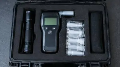 KI-generiertes Bild: Ein digitales Alkoholmessgerät liegt in einem geöffneten Koffer.
