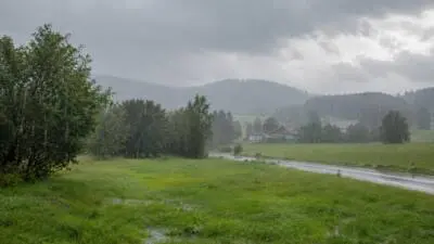 KI-generiertes Bild: Dunkle Wolken ziehen über eine verregnete Landschaft mit nasser Straße.