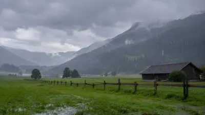 KI-Symbolbild: Eine regennasse Berglandschaft mit grüner Wiese und dunklen Wolken.