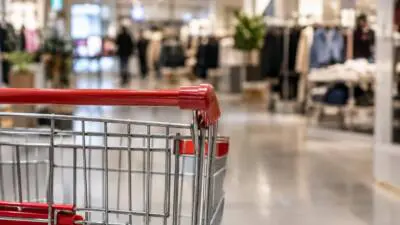 KI-Symbolbild: Ein roter Einkaufswagen steht in einem Bekleidungsgeschäft.