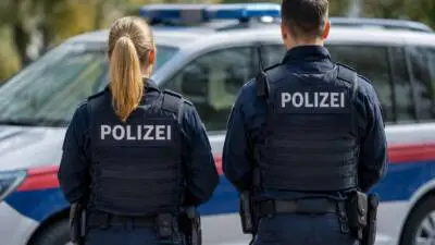 KI-Symbolbild: Polizeikräfte in dunkler Uniform vor einem blau-weißen Streifenwagen.