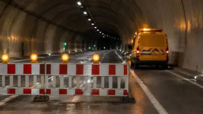 KI-Symbolbild: Absperrgitter und ein gelbes Fahrzeug in einem Tunnel.