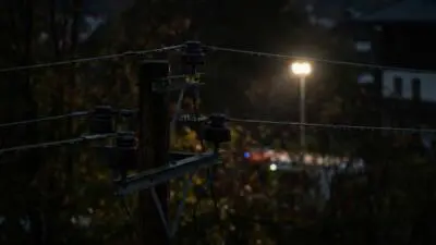 KI-Symbolbild: Stromleitungen an einem Holzmast bei Dunkelheit.