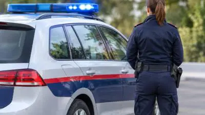 Eine uniformierte Person steht neben einem silbernen Kombi mit blauem Dachblaulicht.
