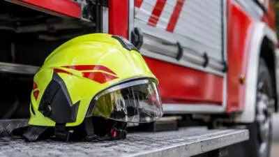 KI-Symbolbild: Ein gelber Schutzhelm liegt auf einer Trittfläche vor einem roten Fahrzeug.