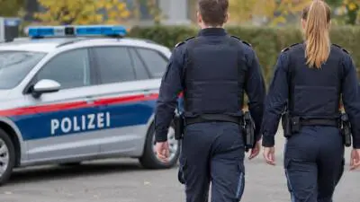 KI-generiertes Bild: Zwei Polizisten in dunkler Uniform neben einem weiß-blauen Polizeiauto.