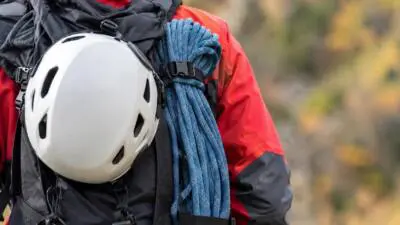 KI-Symbolbild: Weißer Kletterhelm, blaues Seil und schwarzer Rucksack vor unscharfer Landschaft.
