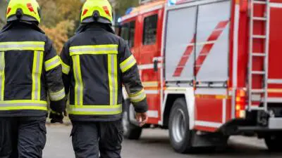 KI-generiertes Bild: Personen in dunkler Schutzkleidung vor einem roten Einsatzfahrzeug.
