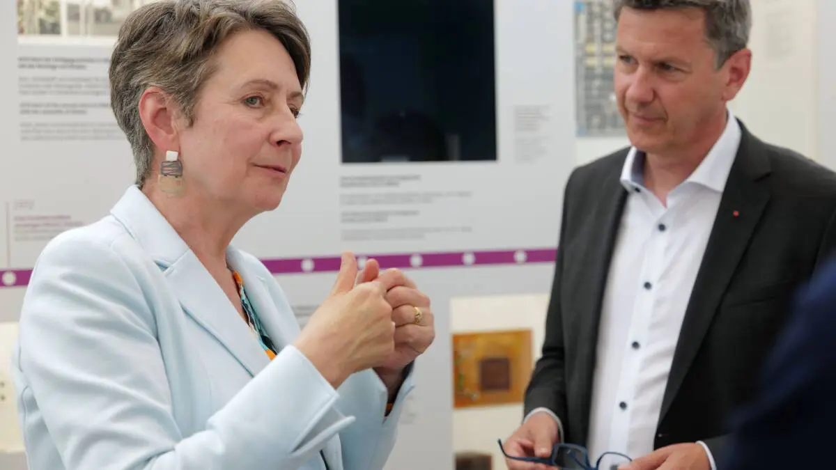 Eine Frau spricht mit einem Mann vor einer Ausstellungstafel.