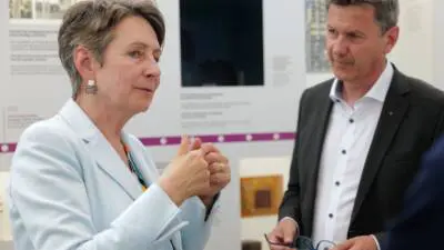 Eine Frau spricht mit einem Mann vor einer Ausstellungstafel.