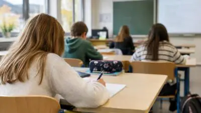 KI-Symbolbild: Lernende sitzen an Tischen in einem hellen Klassenzimmer.
